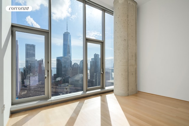 56 Leonard St Unit 44Be, New York City, NY 10013 - unfurnished room with wood finished floors, a view of skyline, and a wall of windows
