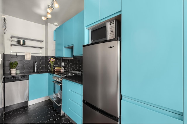 kitchen featuring stainless steel appliances, dark countertops, a sink, open shelves, and blue cabinets