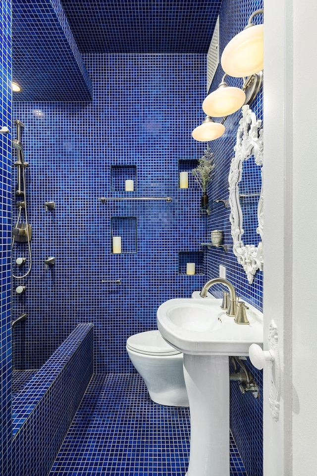 bathroom featuring toilet, tile patterned floors, and tile walls