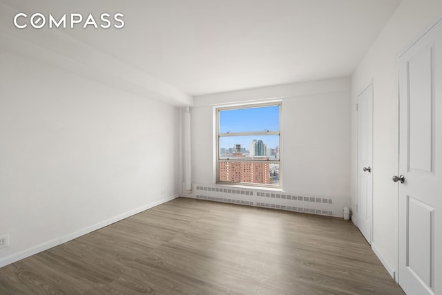 501 W 123rd St Unit 21D, New York City, NY 10027 - unfurnished bedroom with radiator heating unit, wood finished floors, and baseboards