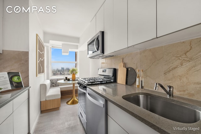 501 W 123rd St Unit 21D, New York City, NY 10027 - kitchen featuring a sink, stainless steel appliances, dark stone countertops, and white cabinetry