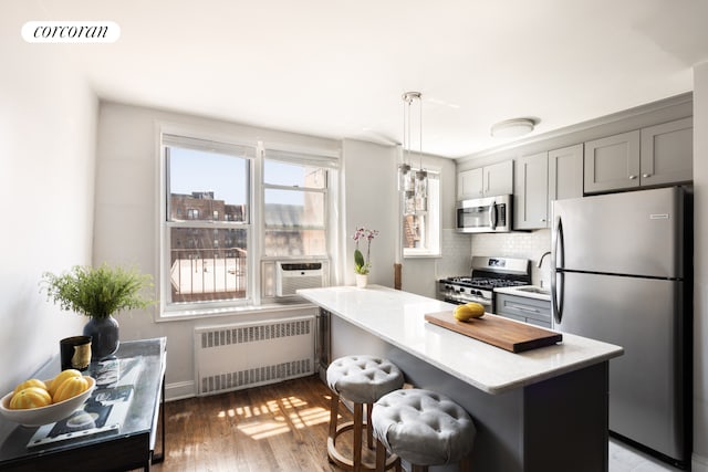 67-30 Clyde St Unit 5P, New York City, NY 11375 - kitchen featuring radiator heating unit, appliances with stainless steel finishes, backsplash, a kitchen bar, and hanging light fixtures