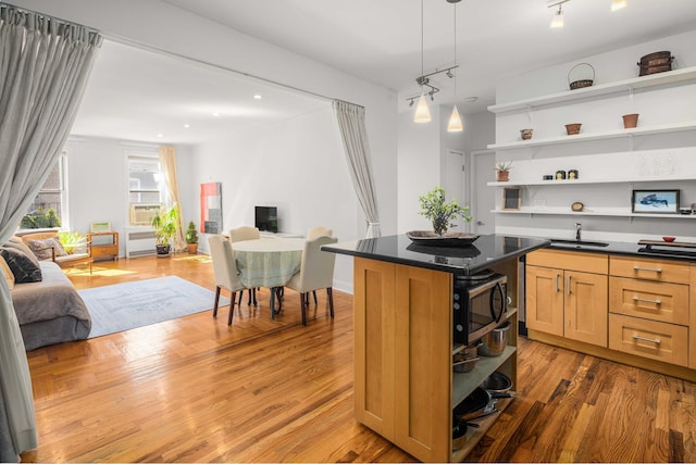 kitchen with open shelves, stainless steel microwave, a sink, open floor plan, and dark countertops