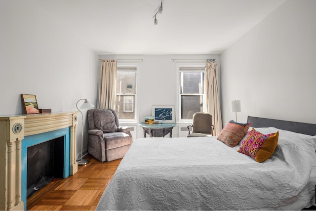 bedroom featuring track lighting and a fireplace