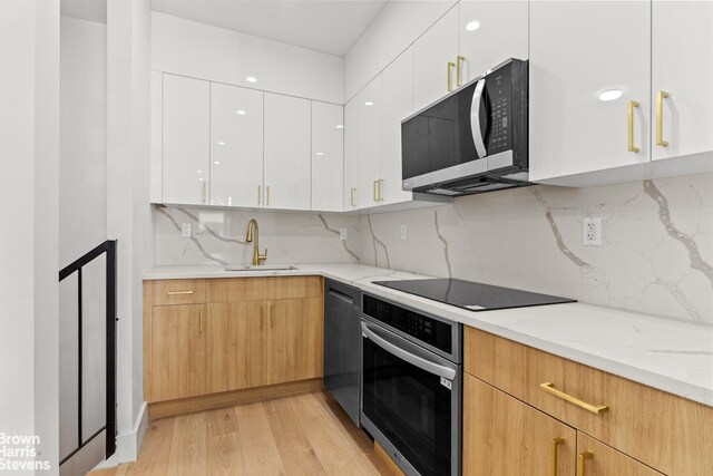 1020 Hancock St Unit 1A, New York City, NY 11221 - kitchen featuring black appliances, modern cabinets, light wood-type flooring, white cabinets, and decorative backsplash