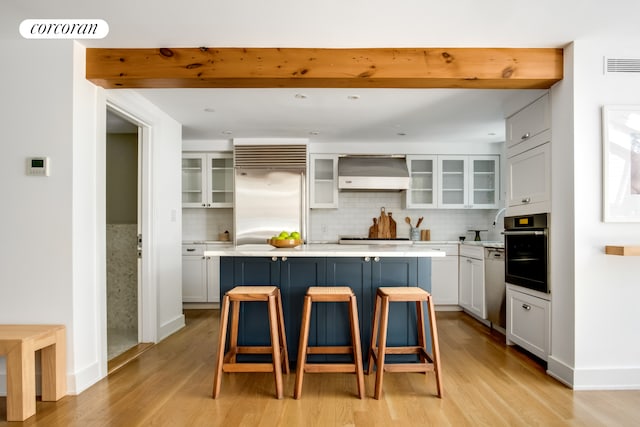 136 E 19th St Unit 1W, New York City, NY 10003 - kitchen featuring ventilation hood, built in refrigerator, black oven, and light wood-style floors
