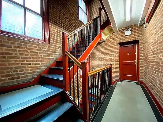 stairs with finished concrete flooring, a wealth of natural light, and brick wall
