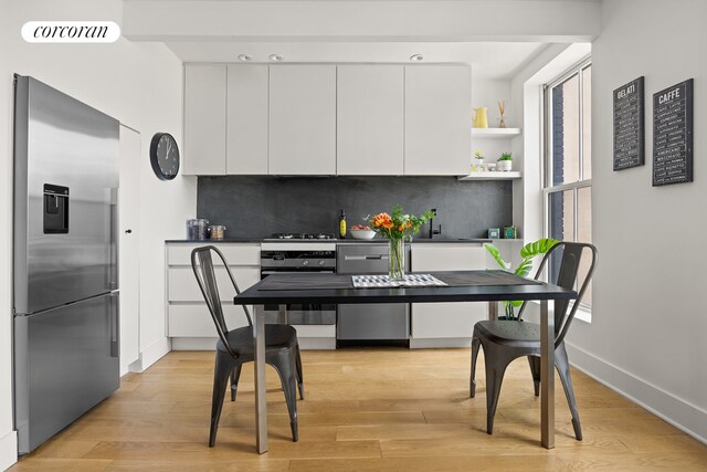 23 N Elliott Pl Unit 4, New York City, NY 11205 - kitchen with stainless steel fridge, white cabinets, decorative backsplash, and light wood finished floors