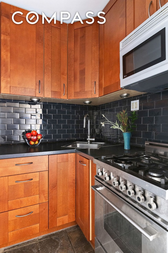 82 Irving Pl Unit 3E, New York City, NY 10003 - kitchen featuring high end stainless steel range oven, white microwave, a sink, tasteful backsplash, and brown cabinets