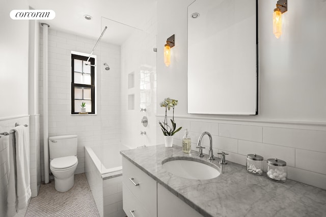 bathroom featuring vanity, bathtub / shower combination, tile walls, toilet, and tile patterned flooring