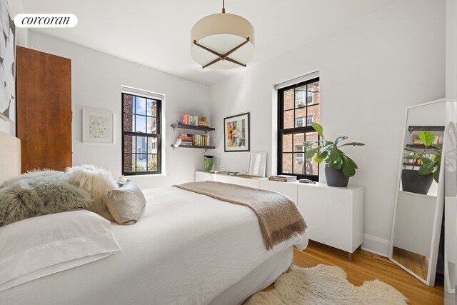 bedroom with baseboards, wood finished floors, and multiple windows