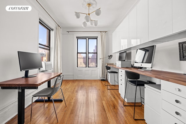 office area featuring built in study area, a chandelier, and light wood-type flooring