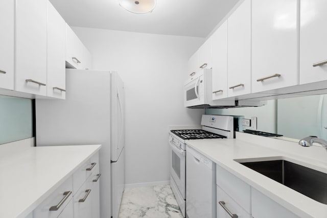 kitchen with white appliances, a sink, light marble finish flooring, light countertops, and white cabinets