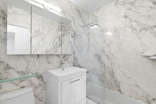 full bath with tub / shower combination, toilet, vanity, and tile walls