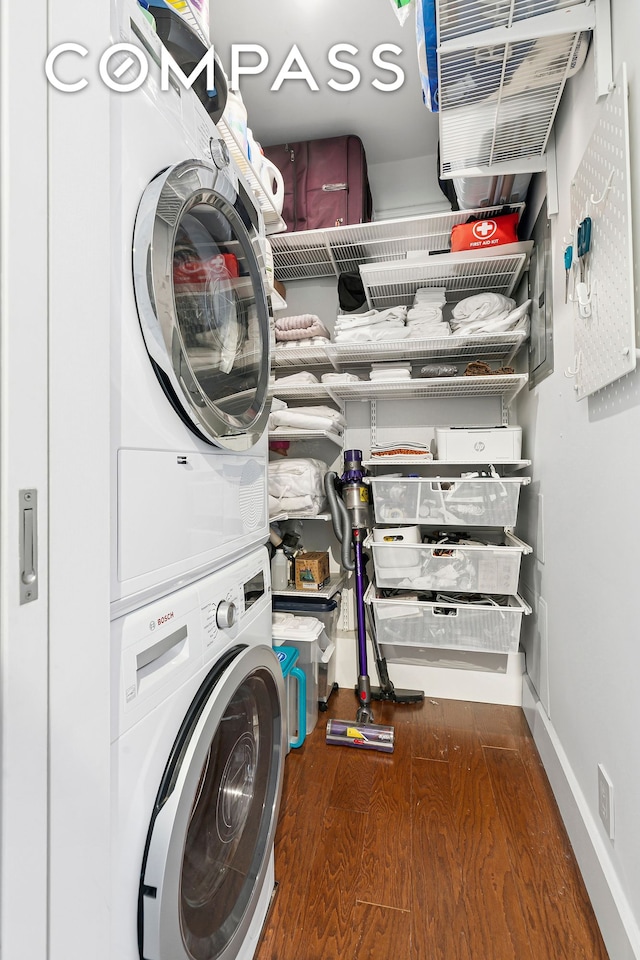 washroom featuring estacked washer and dryer, wood finished floors, and baseboards