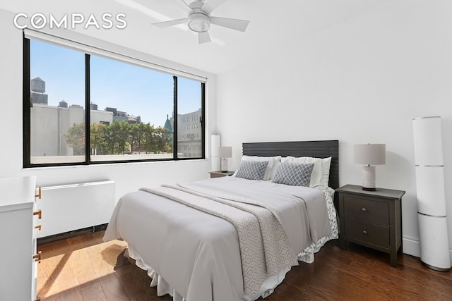 bedroom with wood finished floors, multiple windows, radiator, and a ceiling fan