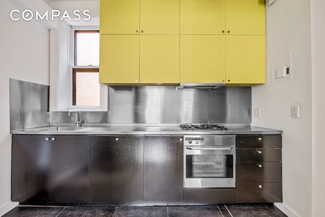 391/2 Washington Sq S Unit 9, New York City, NY 10012 - kitchen featuring stainless steel counters, oven, yellow cabinets, and ventilation hood
