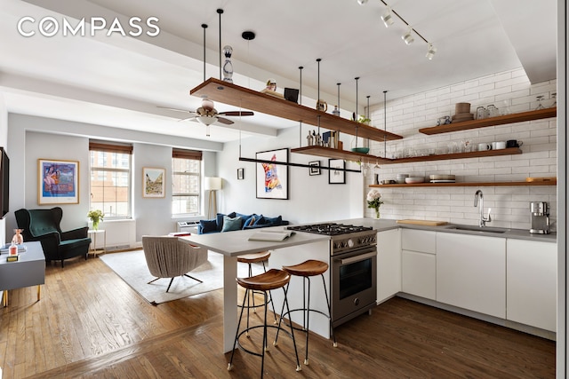 410 W 24th St Unit 9K, New York City, NY 10011 - kitchen featuring high end stove, a sink, white cabinets, open floor plan, and a peninsula