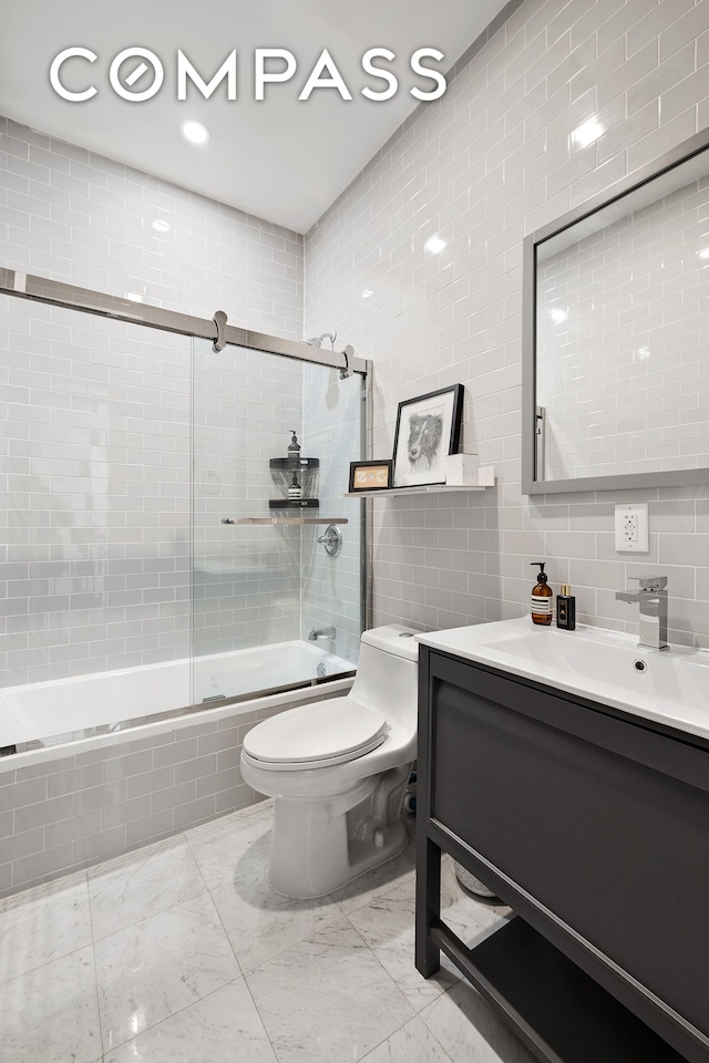 full bathroom featuring tile walls, vanity, tiled shower / bath, toilet, and marble finish floor