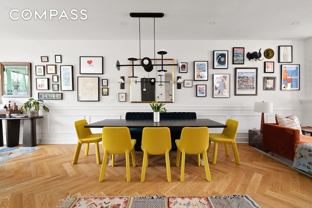 dining area with a decorative wall and a wainscoted wall