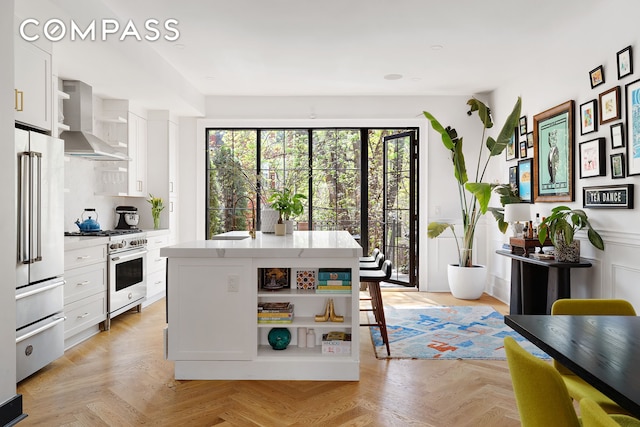 kitchen with open shelves, wall chimney exhaust hood, white cabinets, and premium appliances