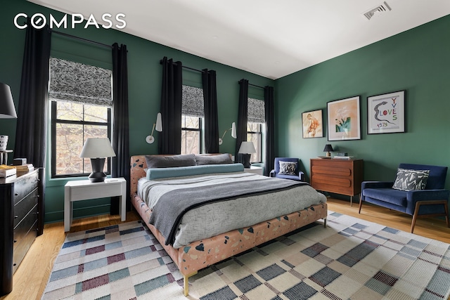 bedroom with multiple windows, light wood-style flooring, and visible vents