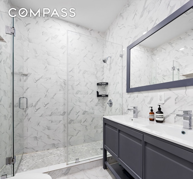 bathroom featuring double vanity, a shower stall, a sink, and marble finish floor