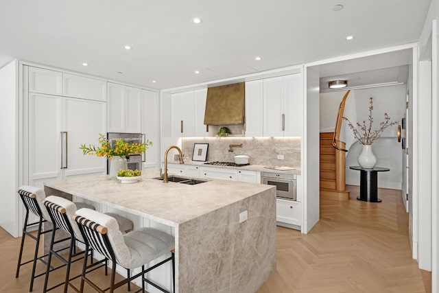 2505 Broadway Unit 2B, New York City, NY 10025 - kitchen featuring a kitchen breakfast bar, an island with sink, custom range hood, a sink, and backsplash