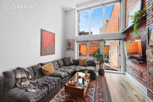 66 N 1st St Unit 1C, New York City, NY 11249 - living room with a towering ceiling, wood finished floors, plenty of natural light, and brick wall