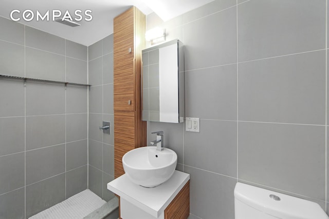 66 N 1st St Unit 1C, New York City, NY 11249 - bathroom featuring tile walls, vanity, toilet, and a tile shower