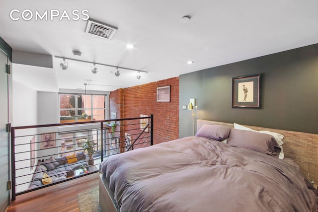 bedroom featuring wood finished floors and track lighting