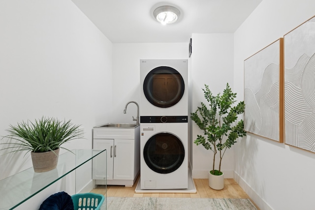 61 W 62nd St Unit 8B, New York City, NY 10023 - washroom featuring cabinet space, stacked washer / dryer, light wood-style flooring, and baseboards