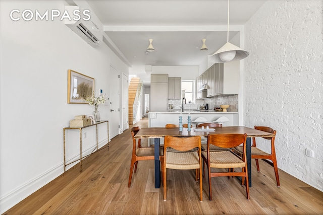 744 Park Pl Unit 4A, New York City, NY 11216 - dining area featuring an AC wall unit, wood finished floors, a textured wall, and baseboards