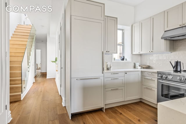 744 Park Pl Unit 4A, New York City, NY 11216 - kitchen featuring electric range, under cabinet range hood, light wood finished floors, and light countertops