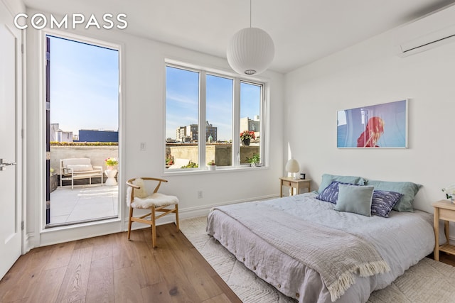 744 Park Pl Unit 4A, New York City, NY 11216 - bedroom with a wall unit AC, wood-type flooring, access to exterior, a view of city, and baseboards