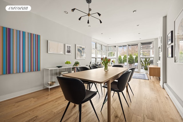 dining space with light wood-type flooring, a chandelier, and baseboards