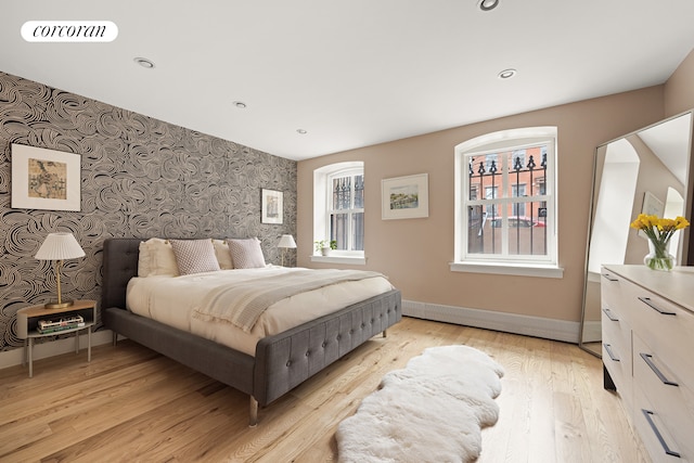 bedroom with wallpapered walls, an accent wall, baseboards, light wood-type flooring, and recessed lighting