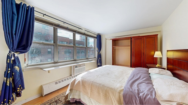 bedroom featuring wood finished floors, baseboard heating, and baseboards