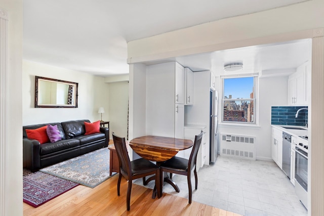 dining area with radiator, light wood finished floors, and baseboards