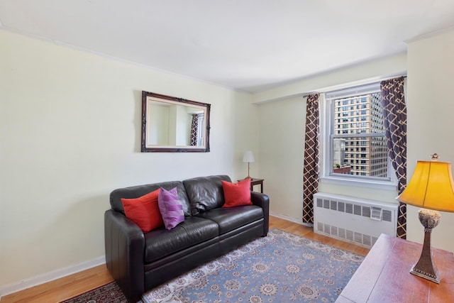 living room with radiator heating unit, wood finished floors, baseboards, and crown molding