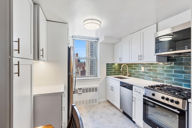kitchen featuring stainless steel appliances, a sink, radiator, light countertops, and tasteful backsplash