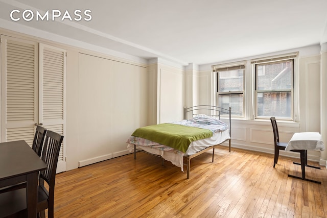 bedroom with light wood finished floors, multiple closets, and a decorative wall