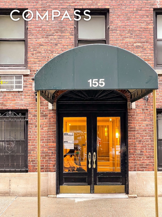 property entrance featuring french doors and brick siding