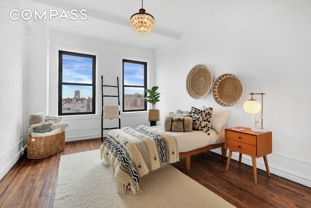 bedroom with wood finished floors, a chandelier, and baseboards