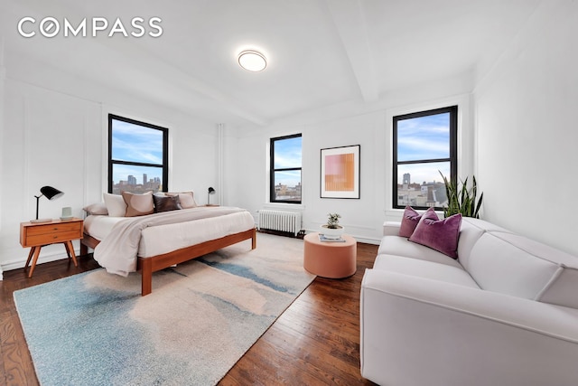 172 E 4th St Unit 8F, New York City, NY 10009 - bedroom with radiator, beam ceiling, and dark wood finished floors