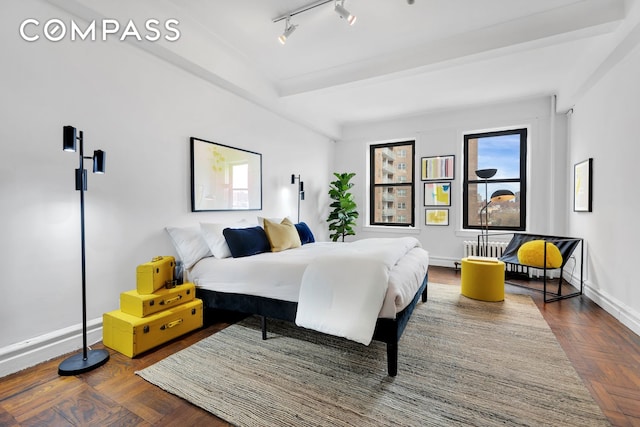bedroom featuring multiple windows, baseboards, and track lighting