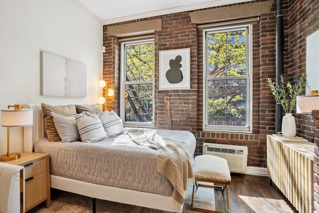 bedroom with brick wall, a wall mounted AC, and wood finished floors
