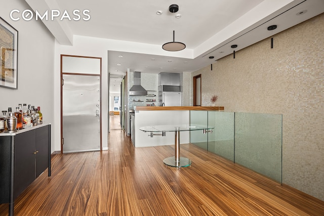 244 W 23rd St Unit 3A, New York City, NY 10011 - bar area with wall chimney exhaust hood, stainless steel built in fridge, and wood finished floors