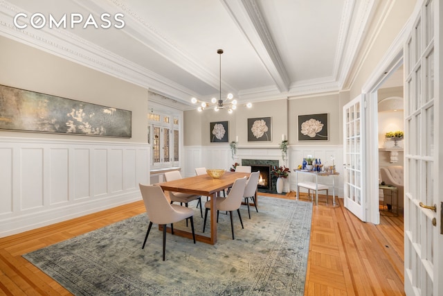 530 W End Ave Unit 9B, New York City, NY 10024 - dining room featuring crown molding, a chandelier, wainscoting, french doors, and a fireplace