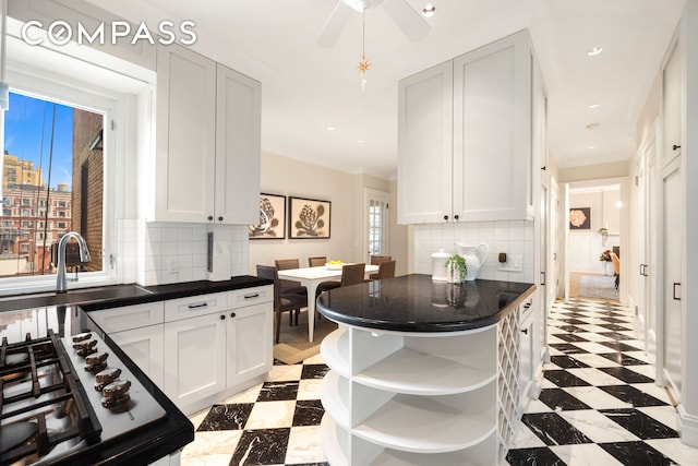 530 W End Ave Unit 9B, New York City, NY 10024 - kitchen featuring open shelves, dark countertops, light flooring, stainless steel gas stovetop, and backsplash